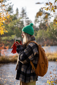 Rear view of woman wearing hat while standing by lake