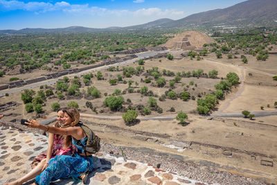Women sitting on landscape against mountains