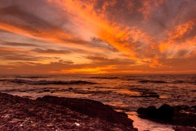 Scenic view of sea against dramatic sky during sunset