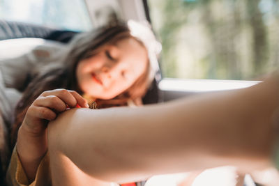 Girl playing with inchworm on knee while sitting in car