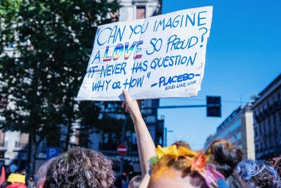 Man amidst crowd holding placard with text during gay pride parade