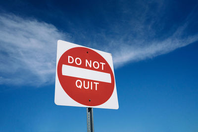 Low angle view of road sign against blue sky