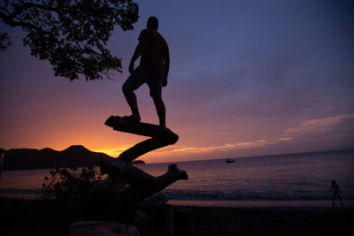 Silhouette men on beach against sky during sunset