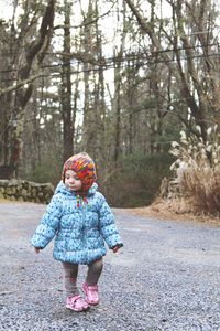 Cute baby girl walking on road against trees