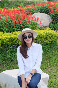 Portrait of beautiful woman wearing sunglasses while sitting against plants