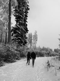 Rear view of woman walking on snow covered field