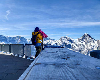 Woman looking through telescope standing by railing