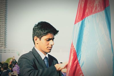 Man holding flag while standing against sky