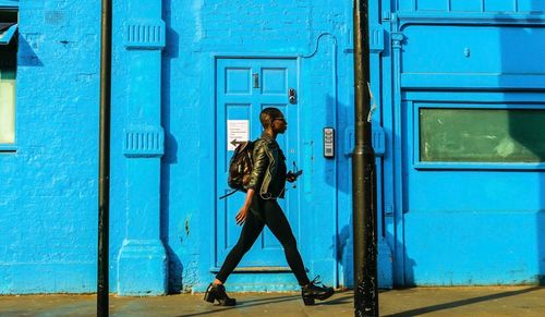 Full length of woman standing against blue door