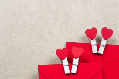 Close-up of heart shape with red envelopes on beige background