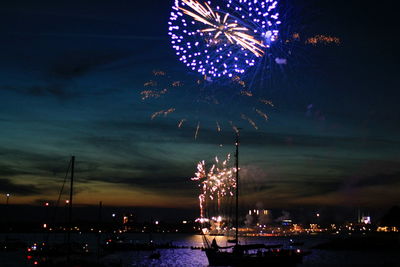 Firework display in city against sky at night