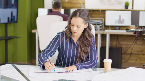 Side view of young businesswoman working at table