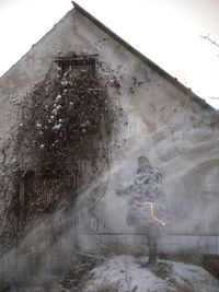 Digital composite image of snow and building against sky