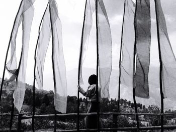 Woman standing by prayer flags against sky