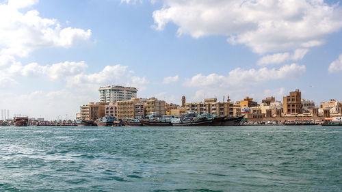 Sea by buildings against sky in city