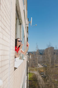 Full length of woman with arms outstretched standing against sky