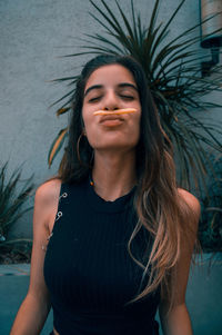 Playful young woman holding french fries outdoors