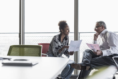 Senior manager discussing documents with young coworker