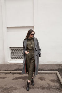 Female fashion model, posing for a full length photo, wearing green suit, urban fashion photography