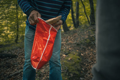 Man holding umbrella while standing on land in forest