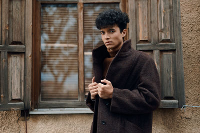 Portrait of young man standing against wall