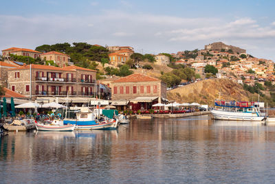 Boats moored on river by buildings in city against sky