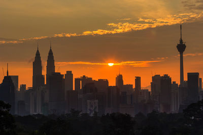 Modern buildings in city against sky during sunset