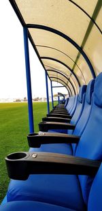 Empty chairs and tables in field against blue sky