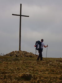 Man walking against large cross on landscape