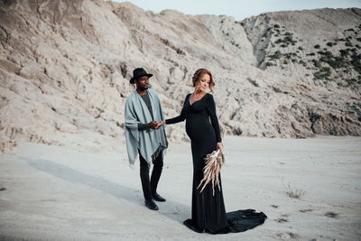 Full length of couple standing on sand in desert