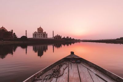 Boat in lake during sunset against taj mahal