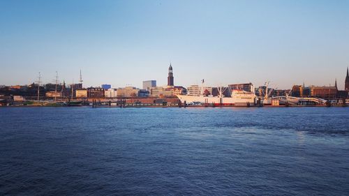 Scenic view of river by city against clear sky