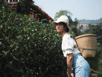 Side view portrait of woman carrying wicker basket at farm