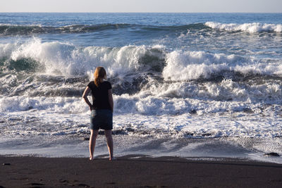Rear view of woman standing on beach against sky