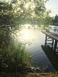 Swimming pool by lake against sky during sunset