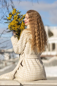 A woman with a bouquet of acacia flowers. the concept of the spring - march 8, easter, women's day.