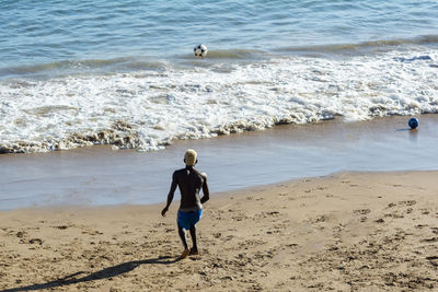 Young model playing sand football on the beach under strong summer sun. salvador bahia brazil.