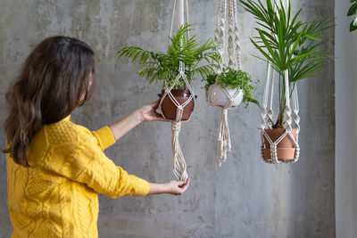 Rear view of woman standing by potted plant