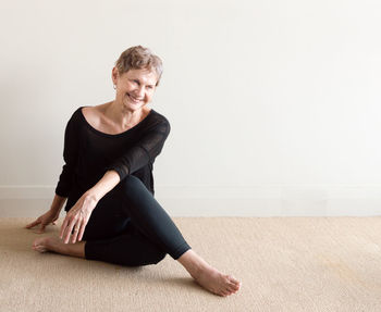 Portrait of smiling young woman sitting against wall