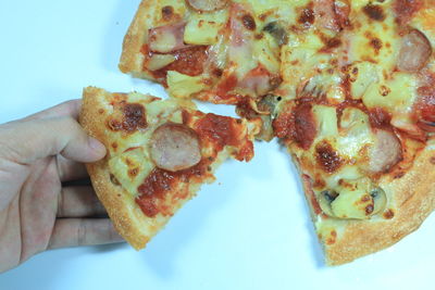 Close-up of hand holding pizza