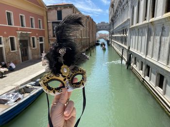 Person holding umbrella by canal in city