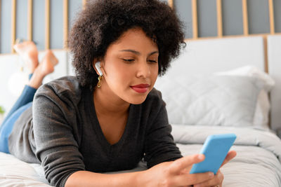 Young woman using mobile phone on bed