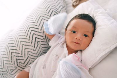 High angle portrait of cute baby boy lying on bed