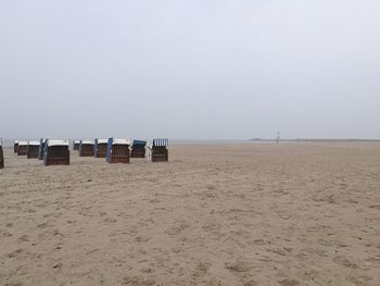 Hooded chairs on beach against clear sky