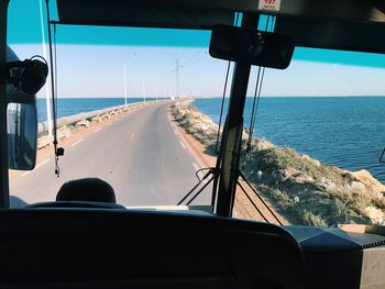 Road by sea seen through bus windshield