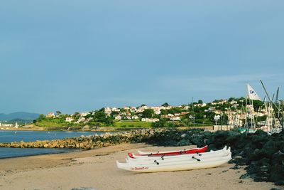 Boats moored at harbor against clear blue sky