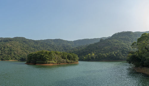 Scenic view of river by mountains against clear sky