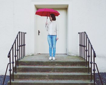 Woman with umbrella standing on railing