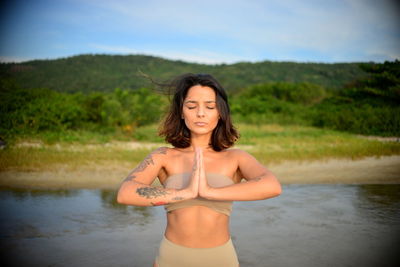 Portrait of young woman standing against lake