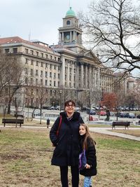 Portrait of mother and daughter standing in city during winter